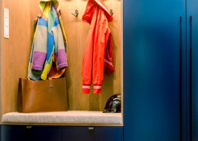 Strefa wejściowa w apartamencie na Ursynowie — zabudowa z siedziskiem, głębokie granatowe fronty i detal organizacyjny.