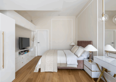 Sypialnia z zabudową RTV i toaletką w jasnych tonach, zaprojektowana z dbałością o detal i funkcjonalność.