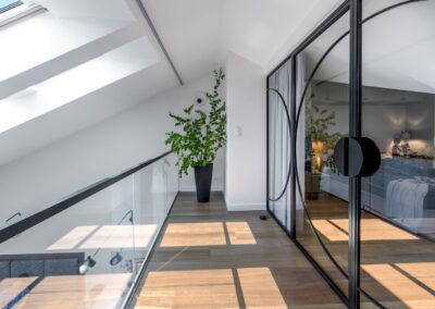 Antresola z loftową ścianką i kotarami — widok od strony sypialni rodziców w apartamencie na Ursynowie.