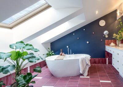 Łazienka rodziców na antresoli — wolnostojąca wanna, granatowa ściana i różowe płytki w apartamencie na Ursynowie.